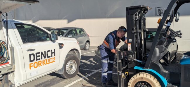 Forklift technician inspecting mast and lifting components during a scheduled service